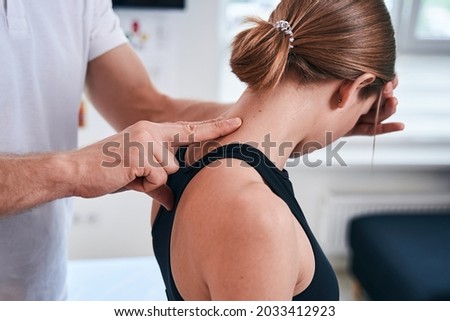 Unrecognized charming female patient sitting in medical office during the manual therapy Royalty-Free Stock Photo #2033412923
