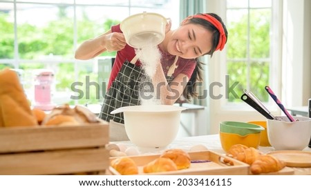A young beautiful Asian woman is baking in her kitchen  , bakery and coffee shop business  Royalty-Free Stock Photo #2033416115