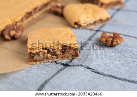 a piece of homemade walnut pie made from shortcrust pastry on a background with a checkered napkin close-up