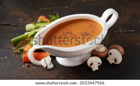 High angle of sauceboat with vegetable sauce with condiments between fresh champignons and carrot with celery pieces Royalty-Free Stock Photo #2033447966