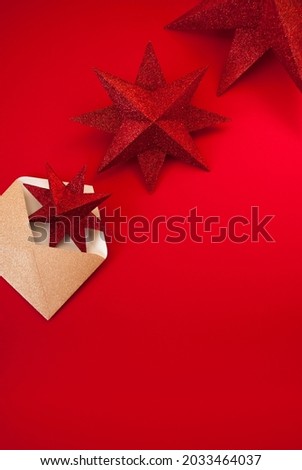 New Year's or Christmas concept with a golden envelope, three glitter red stars on red background. Space for text. Minimal holiday composition. Flat lay, top view