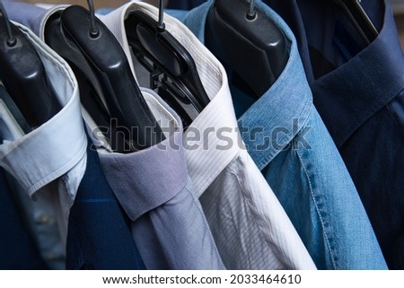 elegant and casual shirts in shades of blue and white. Shirts hang on hangers. Choosing the right outfit.