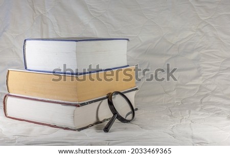 Stack of books and magnifying glass isolated on white background