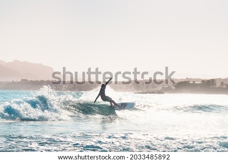 young male surfer riding a wave in the afternoon