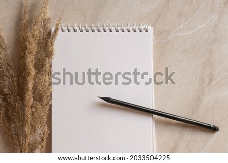 a notebook on a marble background in a minimalist style with spikelets of grass in chocolate tones
