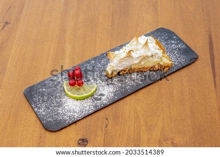 Delicious portion of lemon tart with flambéed cream on top and icing sugar on the lime