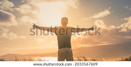 Young man standing on a mountain feeling happy and inspired. Adventure, mental strength, and physical health concept.
 Royalty-Free Stock Photo #2033567609