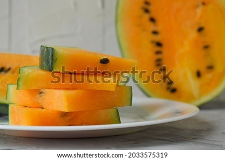 slices of yellow fresh juicy watermelon with black seeds. on a white plate.horizontally Selective focus.