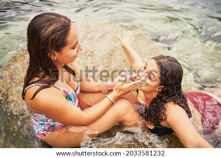 Two young spanish women playing and making mockery faces in beach