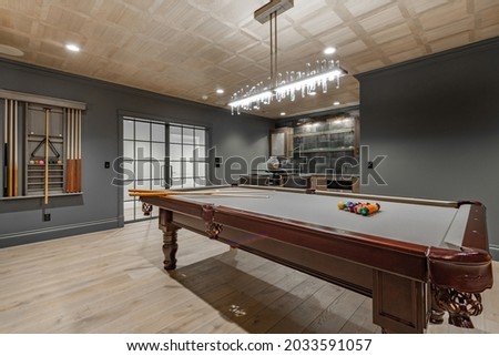 recreation room with large wooden pool table and glass doors Royalty-Free Stock Photo #2033591057