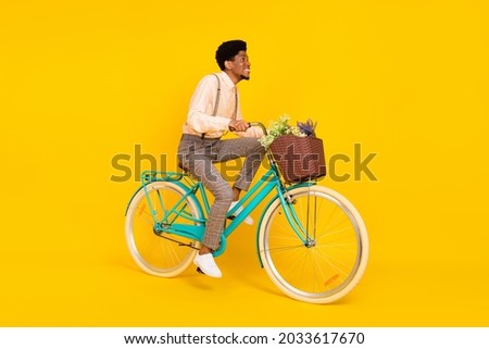 Profile photo of cheerful african guy ride bicycle toothy smile wear suspenders shirt isolated yellow color background