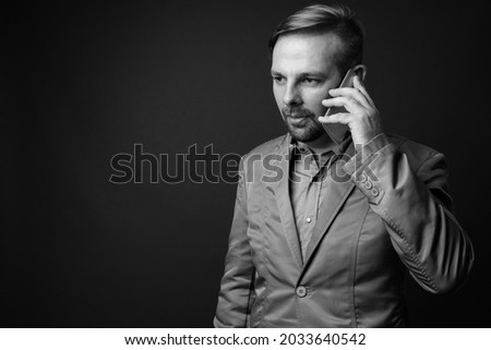 Studio shot of blond bearded businessman with goatee against gray background in black and white