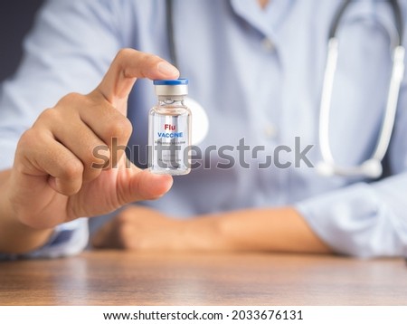Doctor hand holding of a flu vaccine bottle while sitting on a chair in the hospital. Influenza vaccine for protection, treatment, and healthcare concept. Space for text. Royalty-Free Stock Photo #2033676131