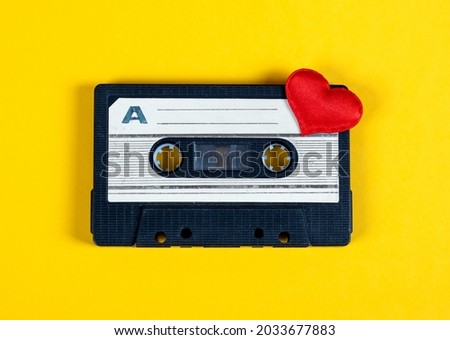 Old Audio Cassette with a Red Heart on the Yellow Paper Background closeup