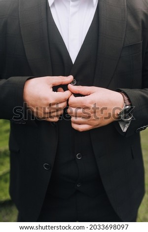 Stylish man, businessman, boss buttons buttons on a black suit with his hands. Business photography.