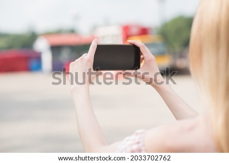Beautiful caucasian blonde girl holding a smartphone in her hands and taking picture