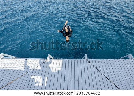 Asian man jump somersault into the sea  Royalty-Free Stock Photo #2033704682