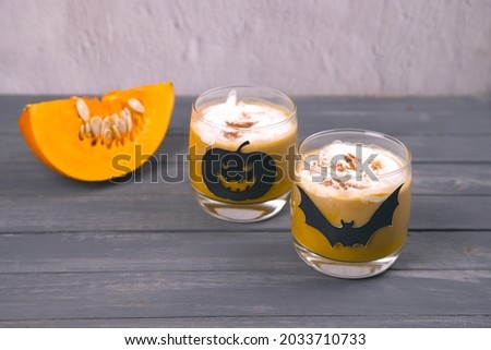 Two glasses of pumpkin latte and Halloween drawings on a dark wooden table. Drinks for halloween