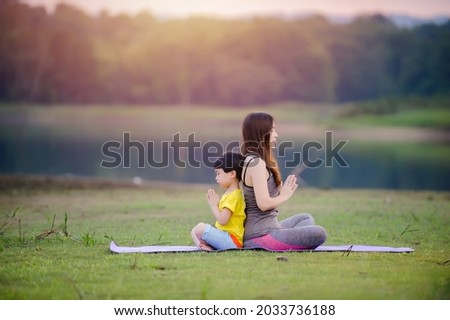 Mother and child  practices yoga and meditates in nature Royalty-Free Stock Photo #2033736188