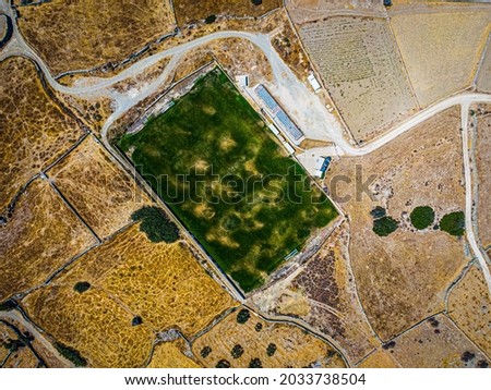 Aerial view on a green football field during drought on sifnos island, Greece 