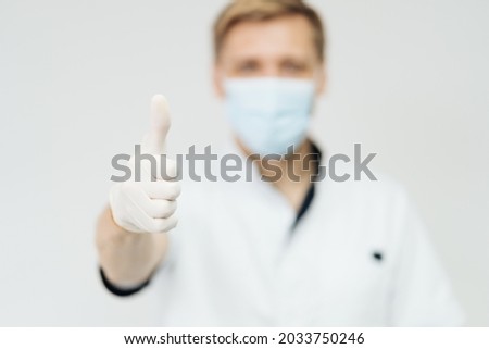 Attractive male doctor show thumbs up hand sign isolated on white background, model is a caucasian man, focu on finger