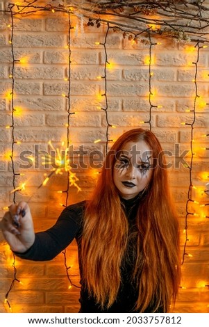 Halloween Witch with sparkler, garland on background.