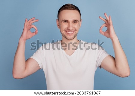 Close up photo of attractive guy holding hands showing okey symbols expressing agreement isolated blue color background