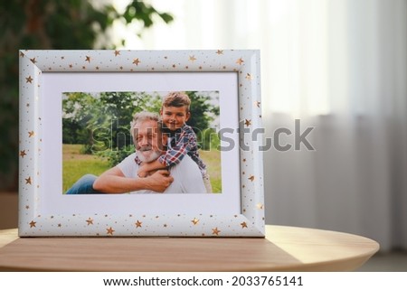 Framed family photo on wooden table in room. Space for text
