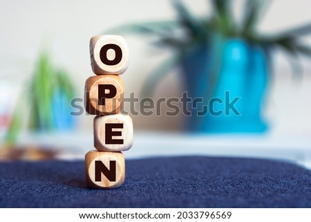 Text 'open' made of wood cubes on blur background. Square wood blocks. Top view