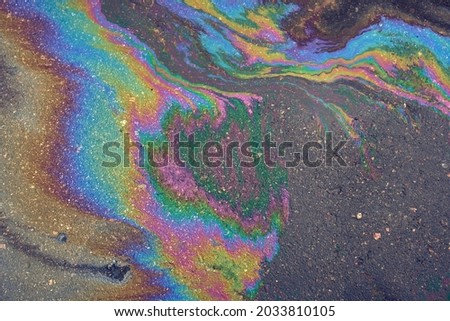 An oil slick on wet asphalt surface. Picture of oil or gasoline spill on asphalt
