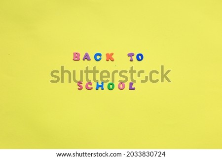 Words from multi colored letters on a yellow background. Expression Back to school. Layout of letters on a yellow background. Many multicolored letters and numbers