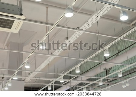 Ceiling with bright lights in a modern warehouse, shopping center building, office or other commercial real estate object. Directional LED lights on rails under the ceiling Royalty-Free Stock Photo #2033844728