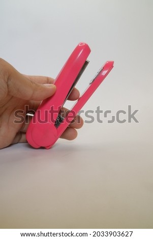 Pink color of big stapler on white isolated background photo