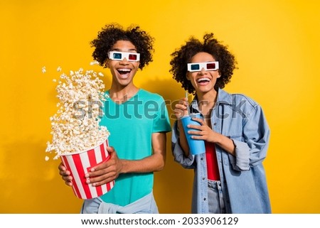 Photo of amazed happy dark skin people couple film glasses pop corn fly drink isolated on yellow color background