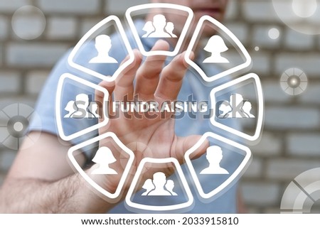 Concept of fundraising. Fundraiser using virtual touchscreen clicks a fundraising word. Royalty-Free Stock Photo #2033915810