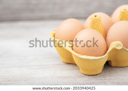 Large brown chicken eggs in yellowcarton packaging on wooden table. close-up, copy space,