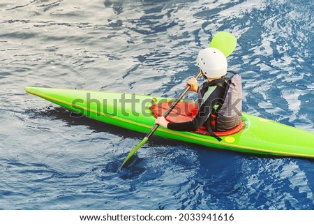 Young boy is engaged in water sports in a kayak or canoe and paddles on a pond during high water in the spring. The concept of extreme sports and hobbies for children