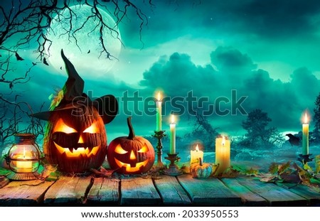 Halloween At Night - Pumpkins With Witch Hat And Candles On Table In Mystery Landscape Royalty-Free Stock Photo #2033950553