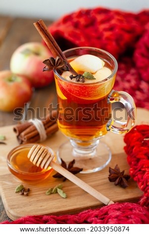 Homemade hot fruit tea with fresh apples, honey, spices: cinnamon, cardamon, anise, clove. Warm autumn drink, delicious healthy beverage. Mulled wine. Cozy fall home atmosphere. Wooden background