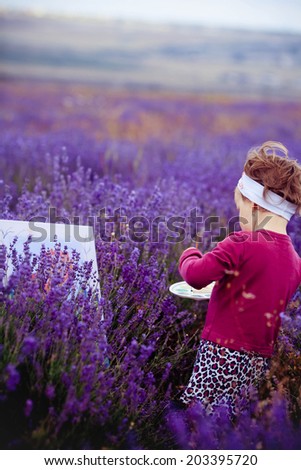the little girl draws a picture in a lavandovy field