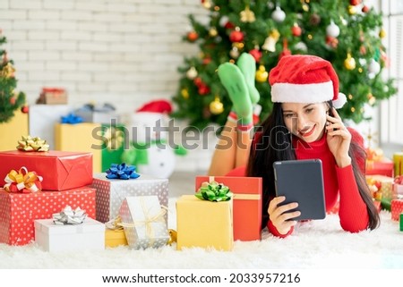 Pretty woman with Christmas costume hold tablet and smile with happiness during Christmas festival.