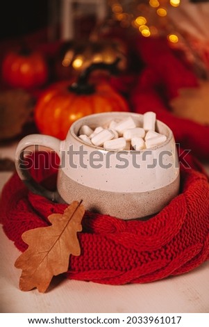 A cup of cocoa with marshmallows and autumn leaves in hands. Atmospheric autumn picture with beautiful bokeh vertical photo, soft focus