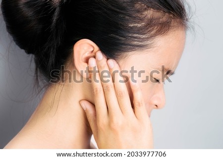 Asian woman suffering from earache. Symptoms of acute external otitis media. Health care concept. Royalty-Free Stock Photo #2033977706