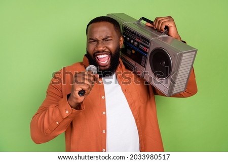 Photo of cool millennial brunet guy sing hold boom-box wear orange shirt isolated on green color background
