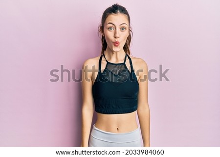 Young brunette woman wearing sportswear scared and amazed with open mouth for surprise, disbelief face 