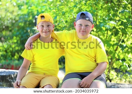 two boys in yellow T-shirts hugging sitting in the park. High quality photo