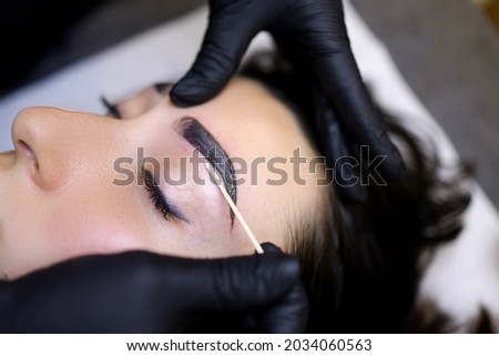 a close-up of the procedure of coloring the eyebrows with paint is performed after the procedure of lamination of the eyebrows Royalty-Free Stock Photo #2034060563