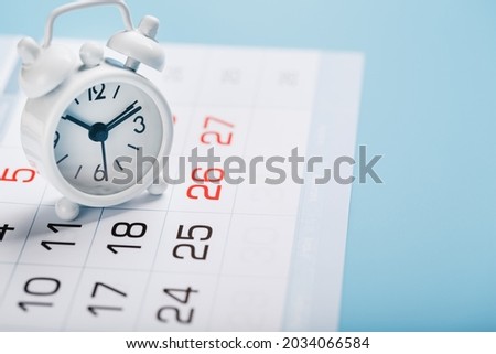 The white alarm clock is on the calendar with dates