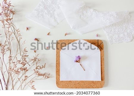 Beige wedding invitations composition. White envelopes, dried flowers, lace textile, sisal rope on white background. Flat lay, top view. Neutral stationary.