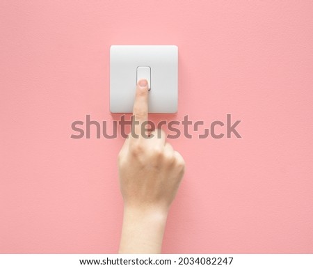One finger switching one off wall-mounted light switch in a close up conceptual view of power, energy and electricity consumption Royalty-Free Stock Photo #2034082247
